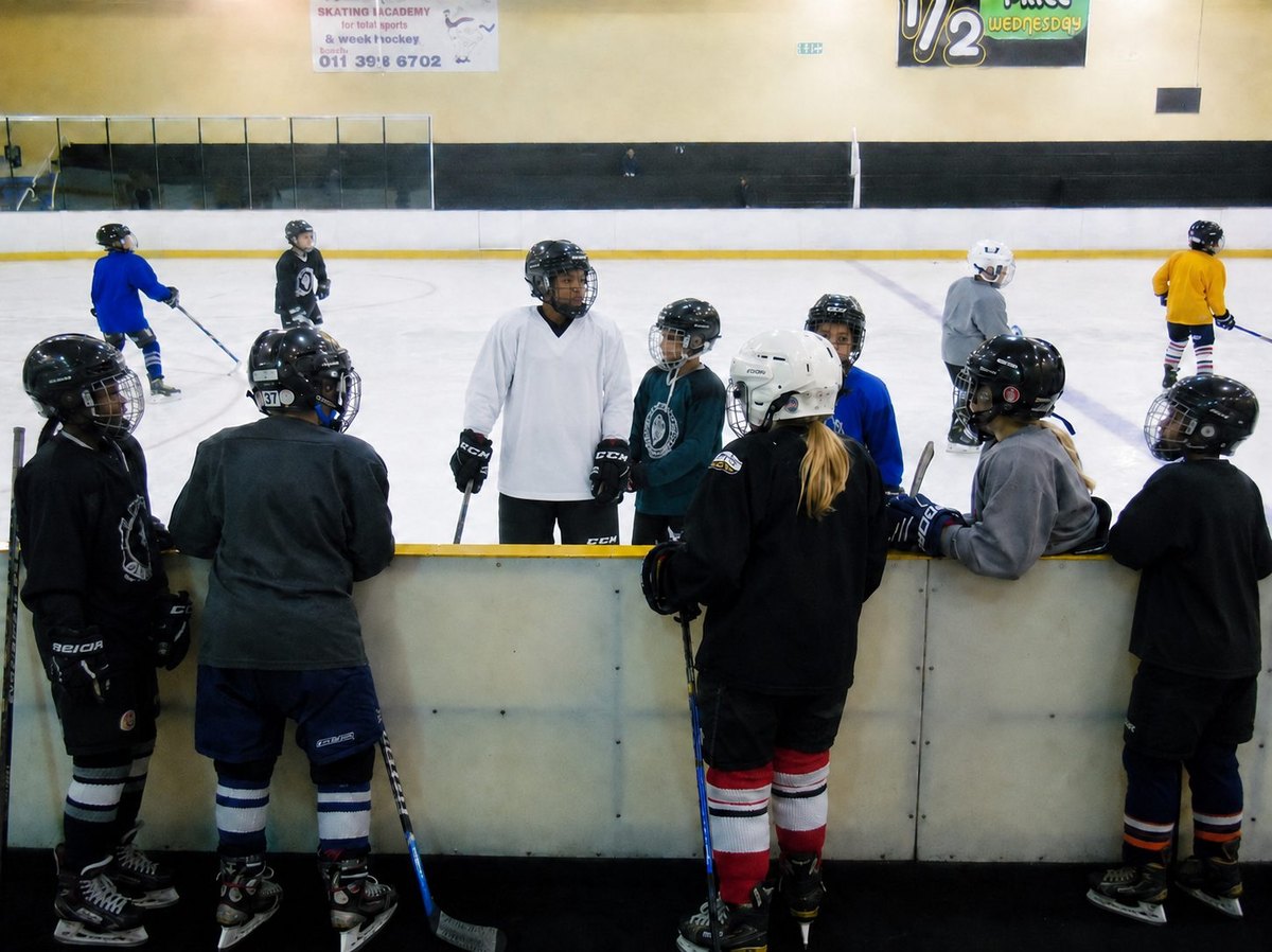 Young ice hockey players gathered at the boards during beginner practice.