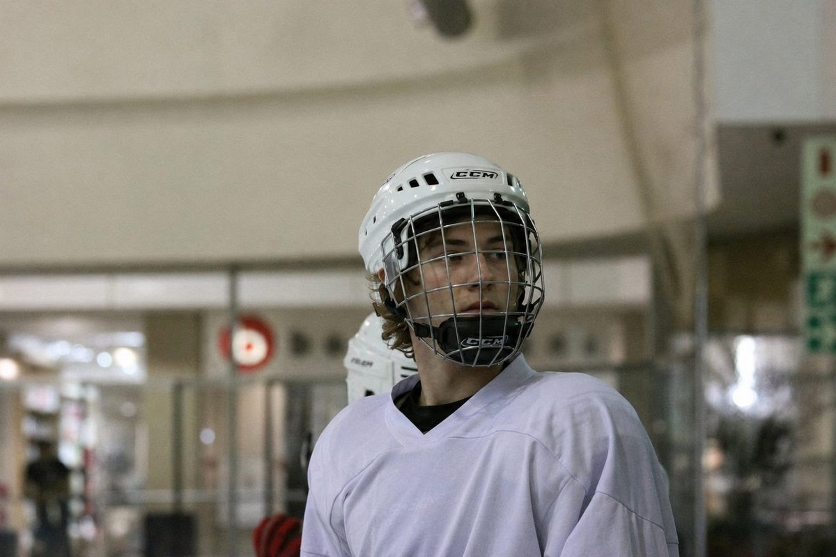 Young hockey player in a white training jersey at the rink.
